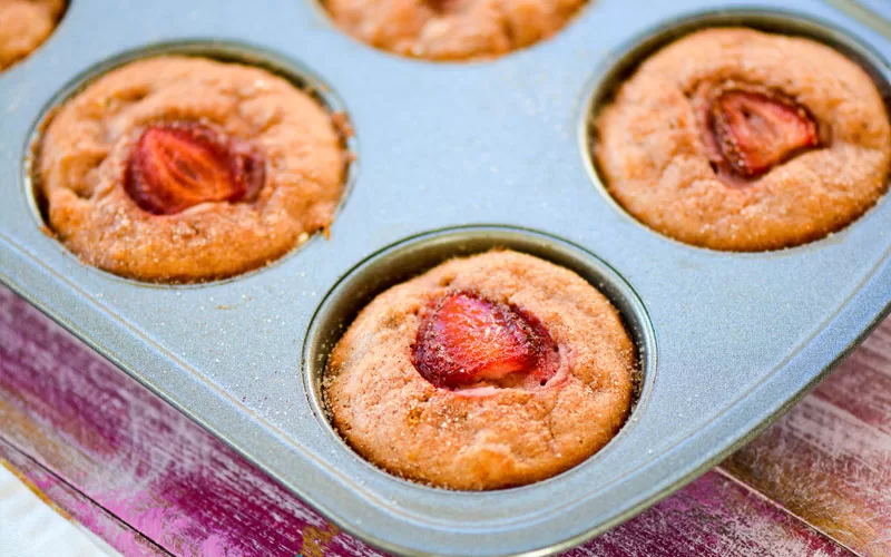 Strawberry cupcakes baked in a muffin pan with sliced strawberries on top