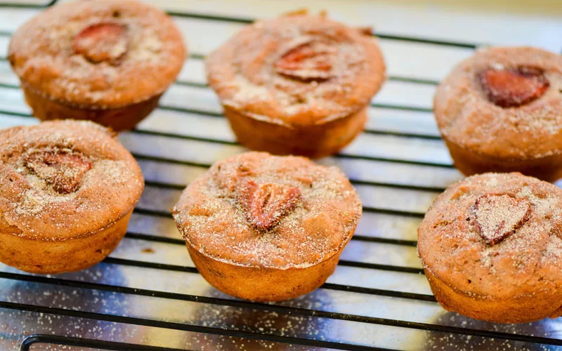Freshly baked strawberry cupcakes cooling on a wire rack with strawberry slices on top
