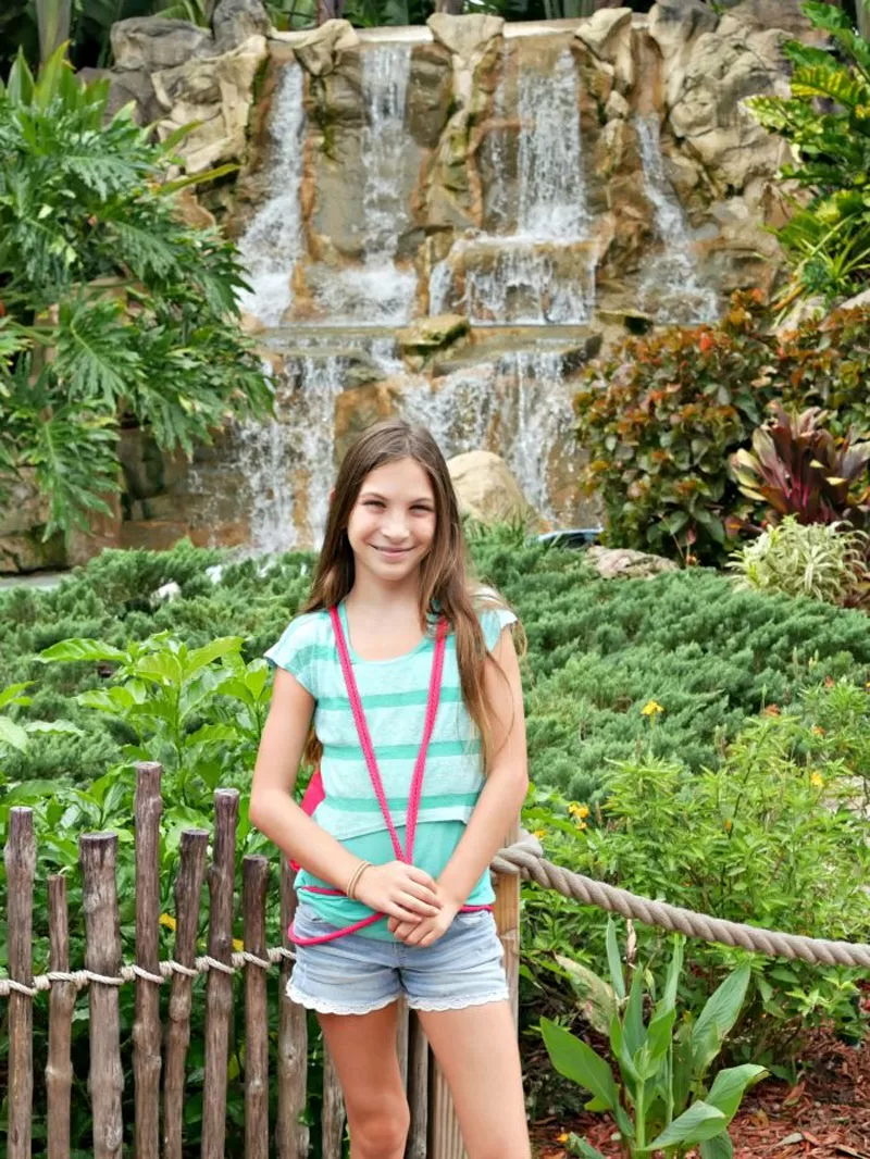 Girl standing in front of a tropical waterfall at Lion Country Safari