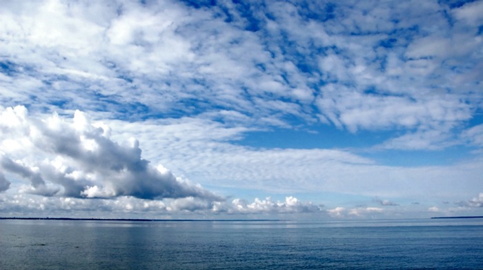 The sea on a background of the blue sky and clouds