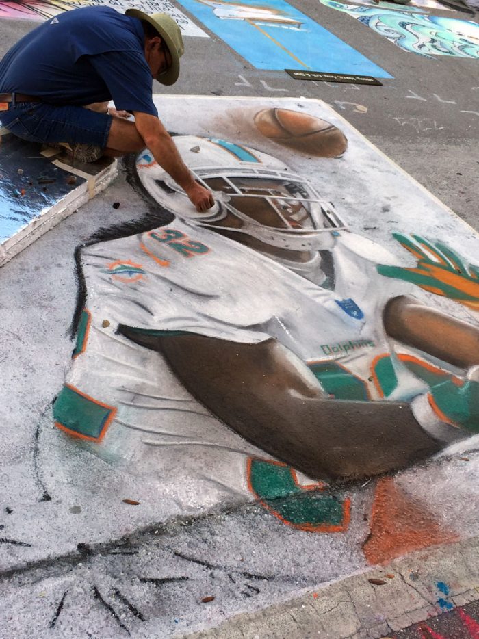 Street Painting Festival Lakeworth Artist working on a large football player chalk drawing at the Lake Worth Street Painting Festival.