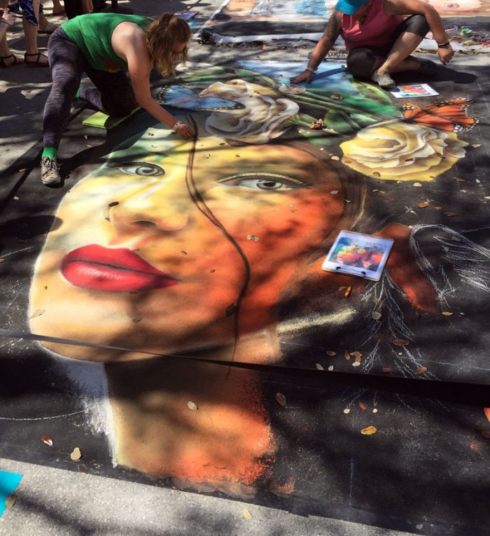 Street Painting Festival Lakeworth Artists working on a large colorful portrait chalk painting on the street during the festival.