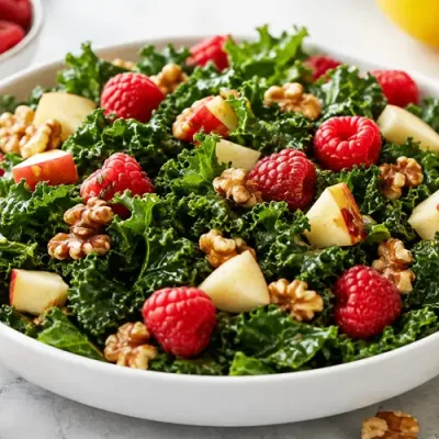 Raspberry apple kale salad with fresh raspberries, diced apples, toasted walnuts, and lemon-honey dressing.