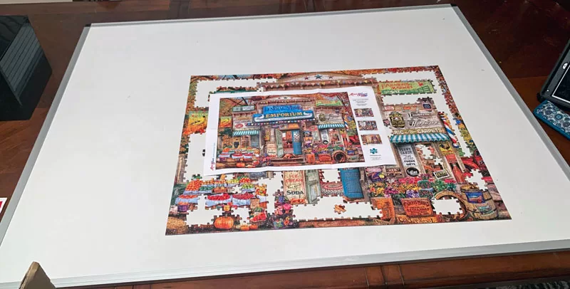 Partially completed puzzle on a large white board placed on a dining room table.