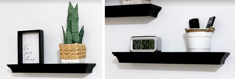 Black floating shelves displaying a framed sign, potted plant, digital clock, and remote controls in a home gym.