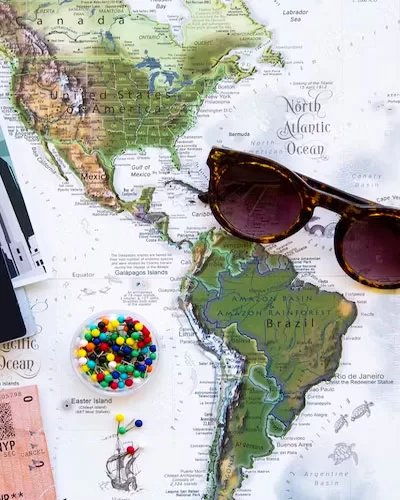 Passport, sunglasses, and travel tickets arranged on a world map
