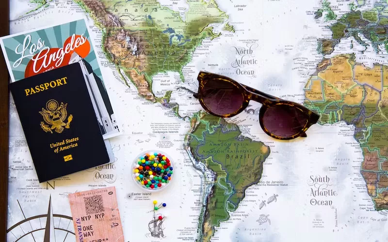 Passport, sunglasses, and travel tickets arranged on a world map