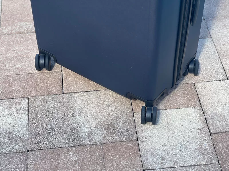 Close-up of LEVEL8 suitcase spinner wheels on a paved outdoor surface.