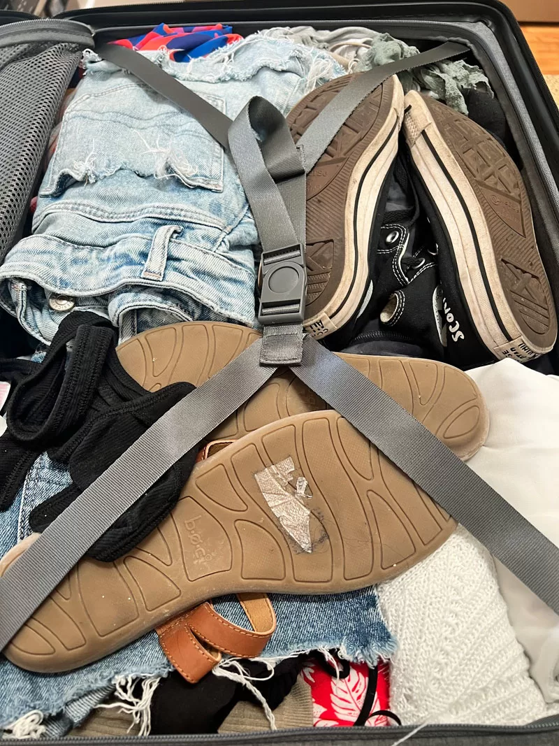 Packed LEVEL8 suitcase with clothing and shoes secured under the X-strap compression system.
