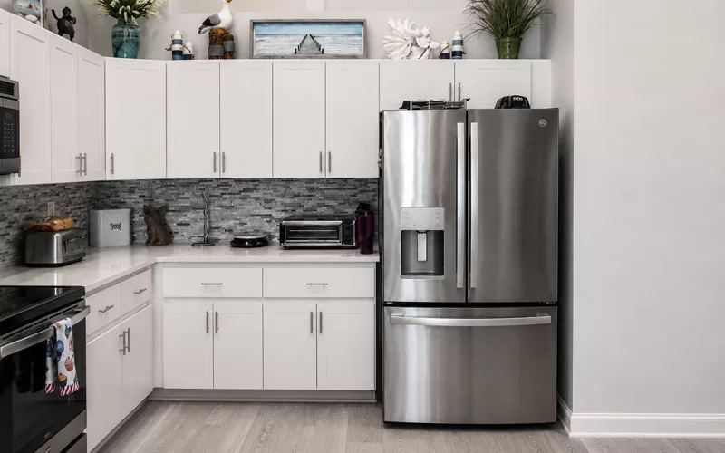 GE GFE26JYMFS stainless steel French door refrigerator in kitchen with bottom freezer drawer and water dispenser