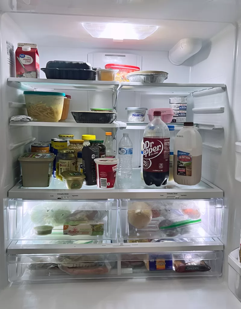 Inside view of GE GFE26JYMFS French door refrigerator with adjustable shelves, climate-controlled drawers, and organized food storage