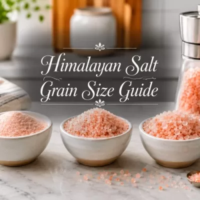 Bowls of different pink Himalayan salt grain sizes with a salt grinder on a bright kitchen counter.