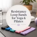 Resistance loop bands on a yoga mat with a water bottle, Pilates ball, towel, and centered title graphic for yoga and Pilates.