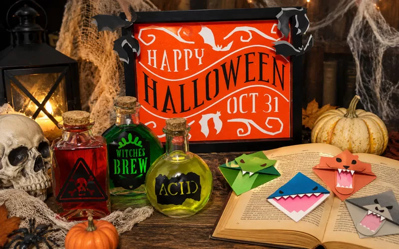 Halloween Cricut crafts displayed with potion bottles, a Halloween sign, monster bookmarks, pumpkins, a skull, and candlelight