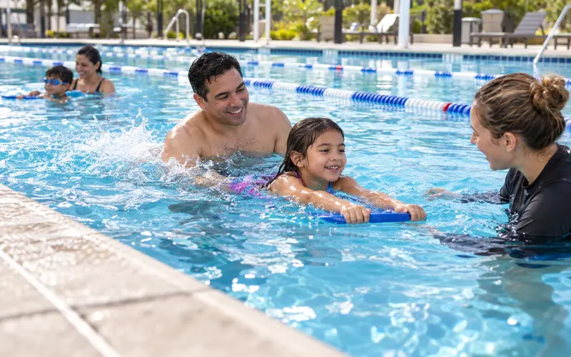 Parent and child practicing swimming skills together in a community pool